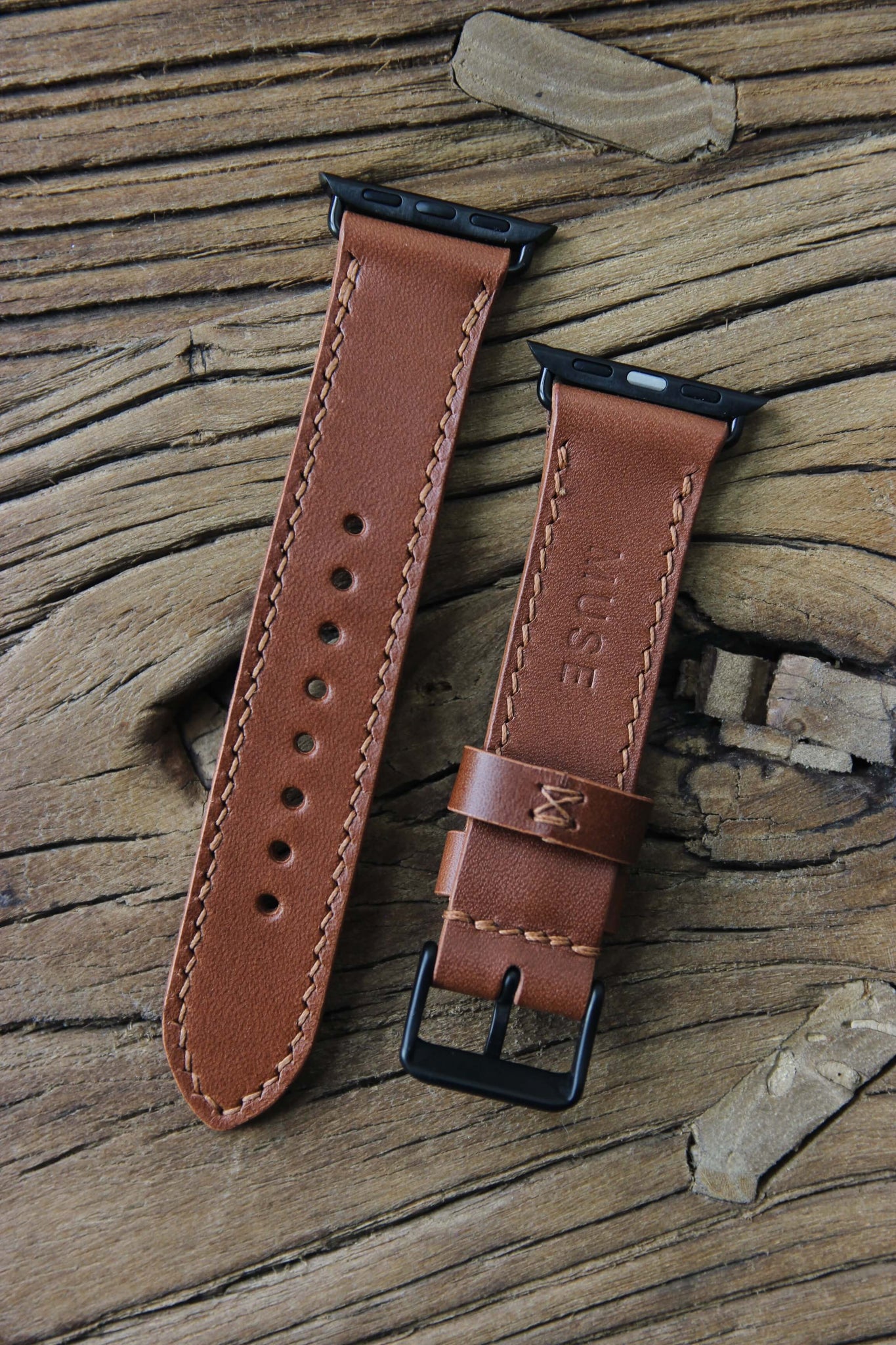 Nahaufnahme eines Apple Watch Lederarmbands in Braun auf einem Holzhocker.
