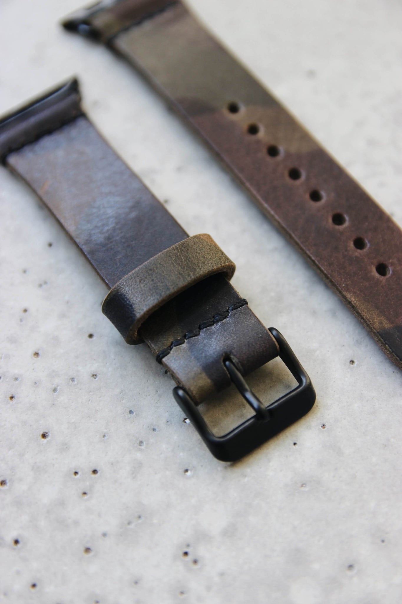 Apple Watch Lederband in Camouflage in Nahaufnahme auf einem Betonuntergrund.