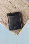 Auf einer Holzplatte liegt ein Kreditkartenetui aus Leder in Camo.