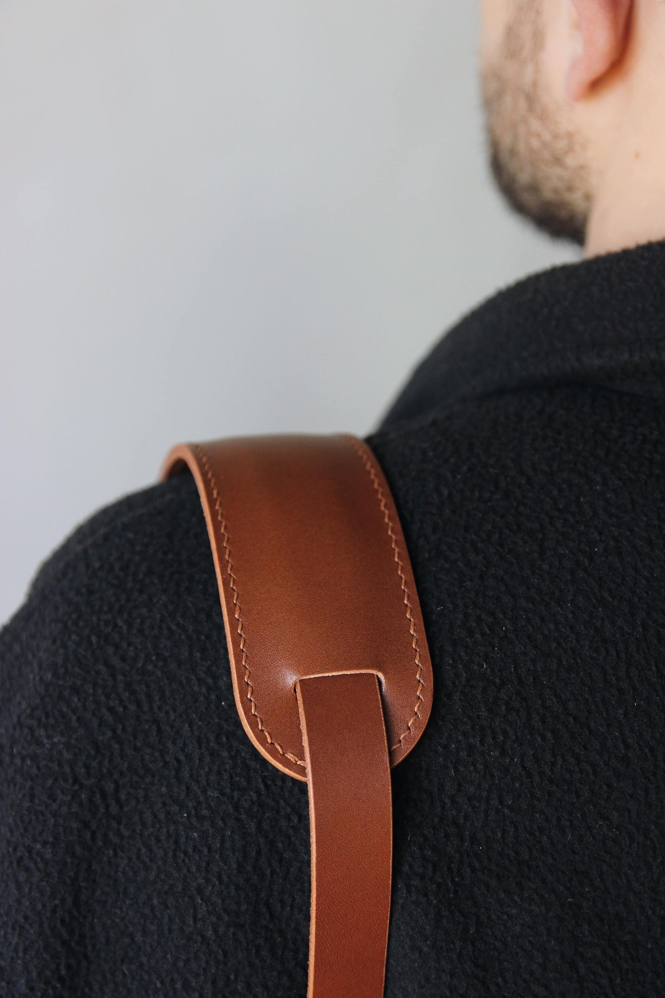 Schulterpad von einem Leder Kameragurt in Braun in Nahaufnahme und über der Schulter getragen.