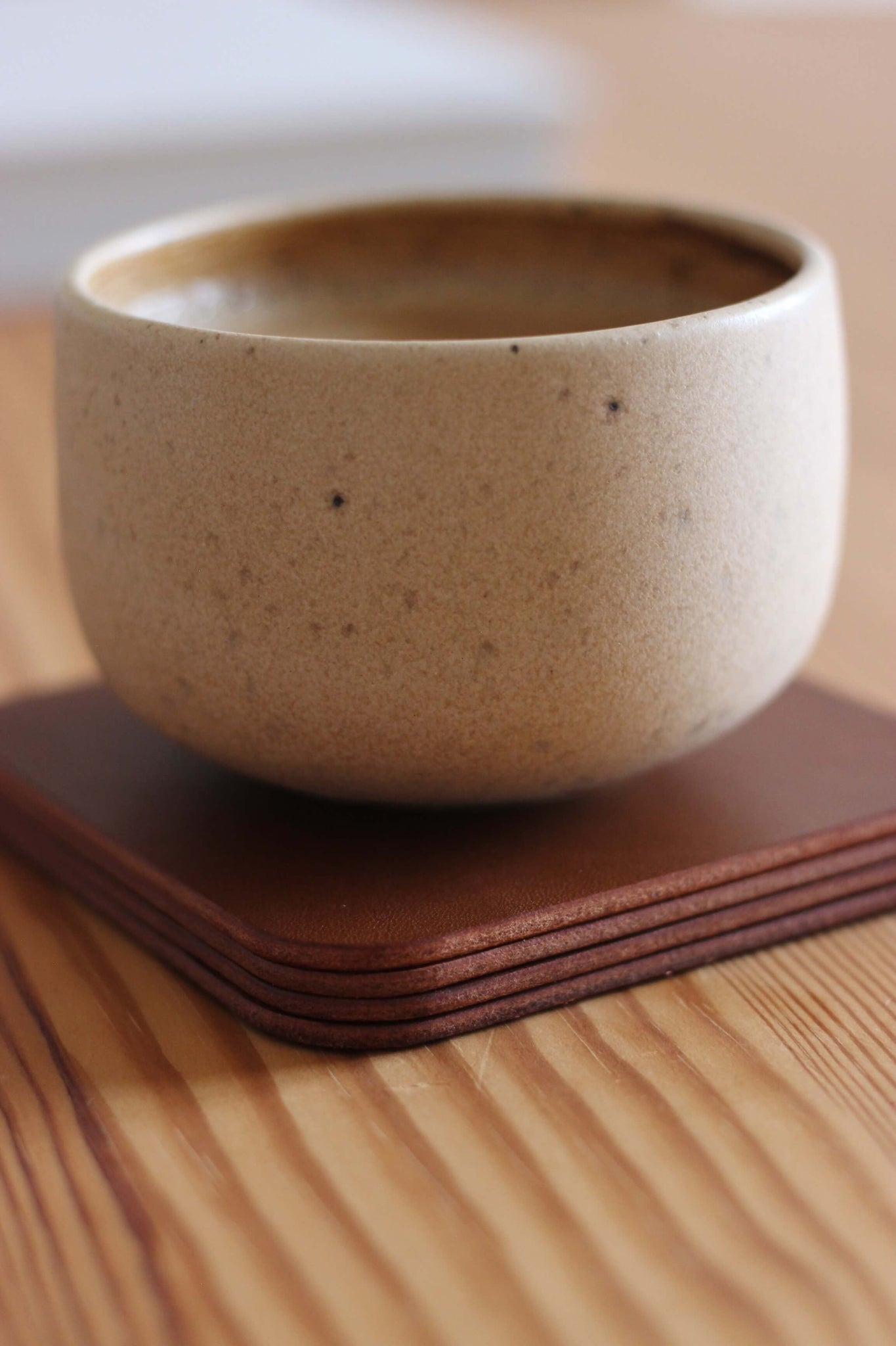 Auf einem Stapel Leder Untersetzer in Braun steht eine Kaffeetasse.