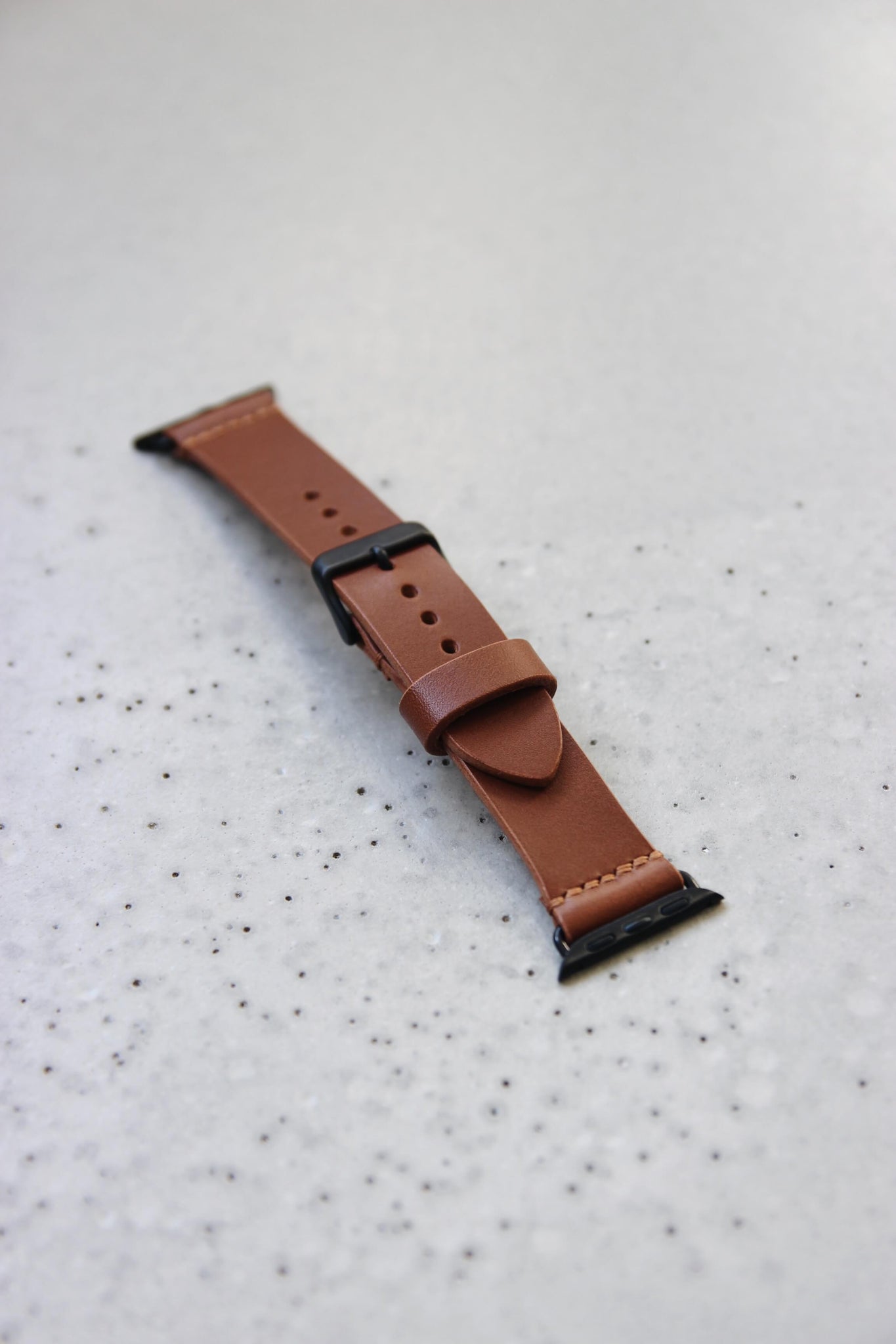 Apple Watch Lederband in Braun auf einem Betonboden liegend.