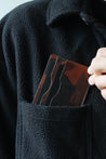 Kartenetui aus Leder in Camouflage wird in eine Brusttasche eines schwarzen Oberteils gesteckt.