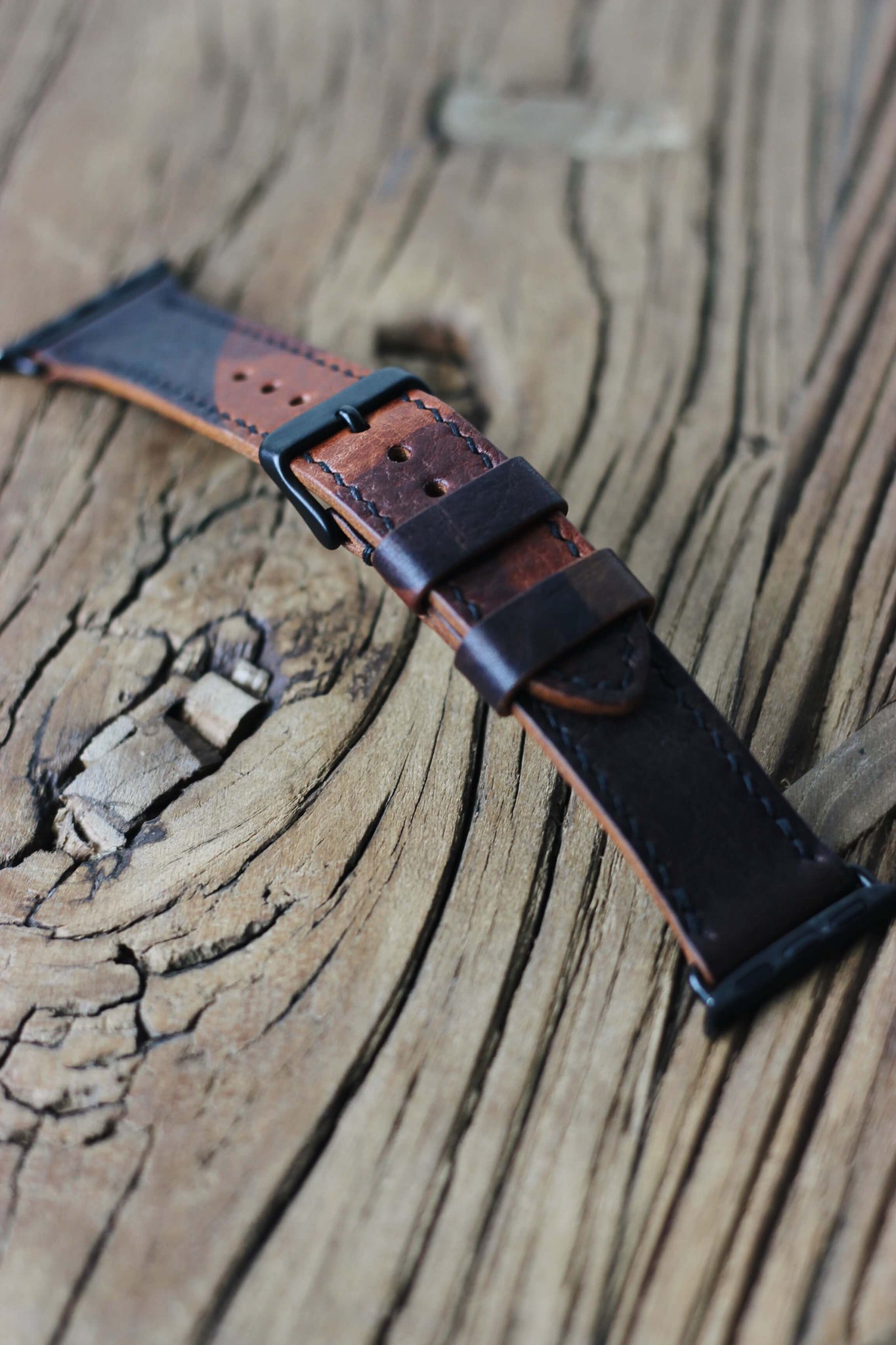 Apple Watch Lederarmband in Camo in der Seitenansicht auf einem Holzhocker.