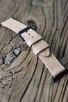 Apple Watch Lederarmband in Natural in der Seitenansicht auf einem Holzhocker.