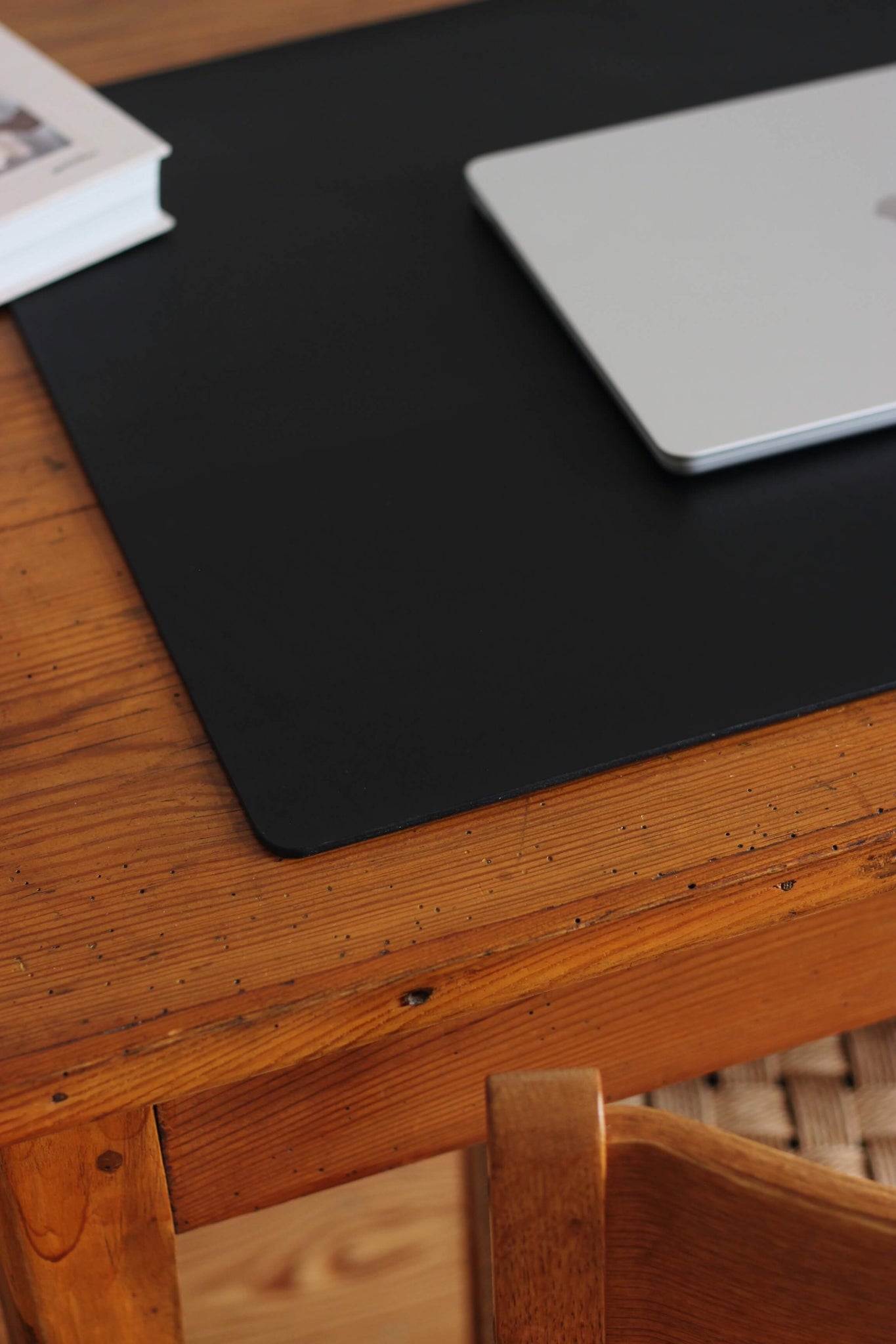 Ausschnitt einer Leder Schreibtischunterlage in Schwarz auf einem Schreibtisch aus Holz.