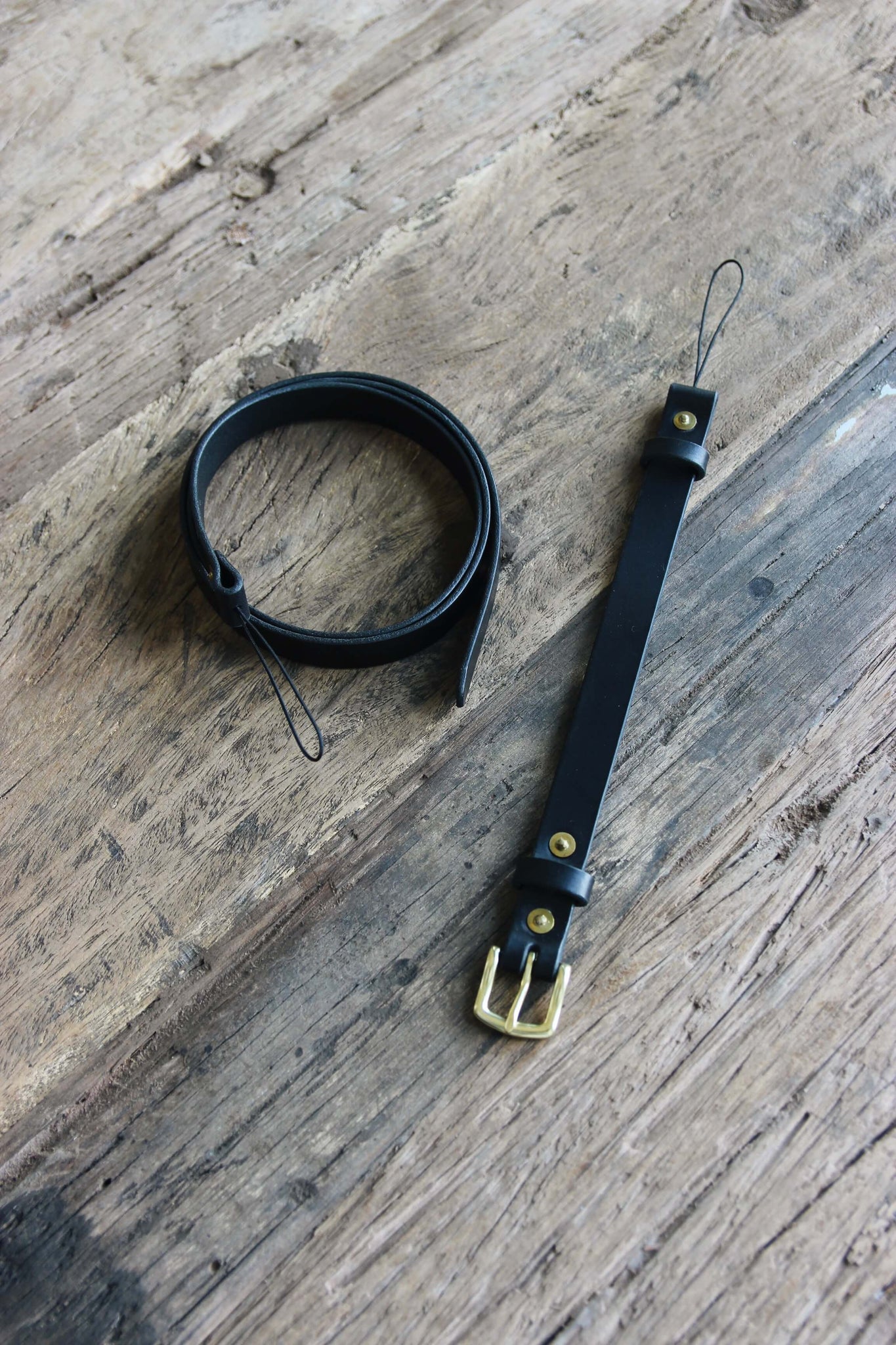 Leder Kameragurt in Schwarz auf einem Holztisch.