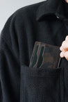 Kartenetui aus Leder in Camo wird in eine Brusttasche eines schwarzen Oberteils gesteckt.