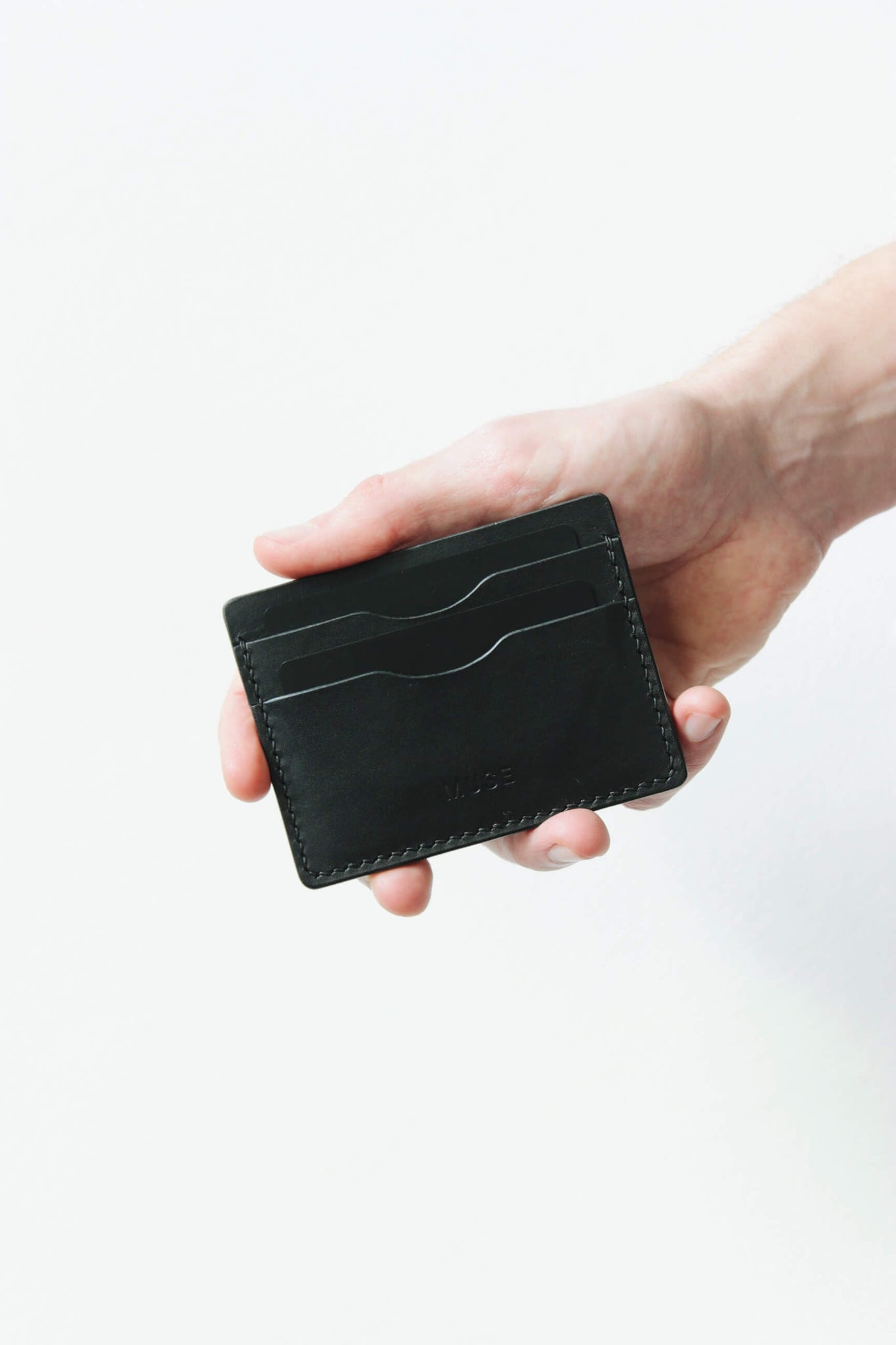 Eine Hand hält ein Kartenetui aus Leder in Schwarz.