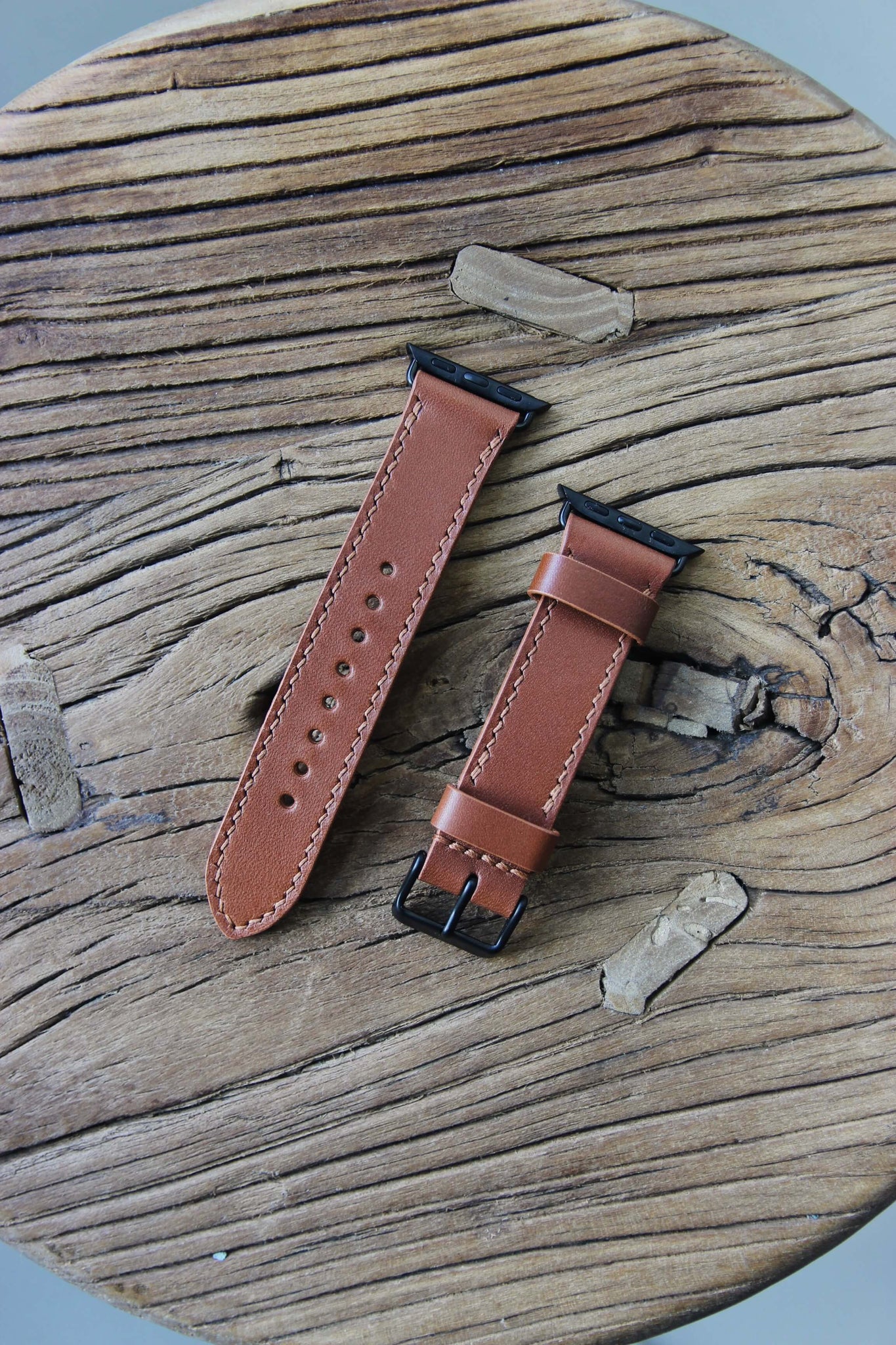 Apple Watch Lederarmband in Braun auf einem Holzhocker liegend.