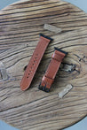 Apple Watch Lederarmband in Braun auf einem Holzhocker liegend.