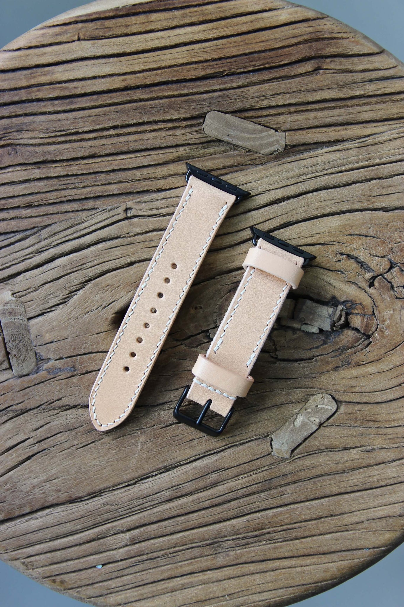 Apple Watch Lederarmband in Natural auf einem Holzhocker liegend.