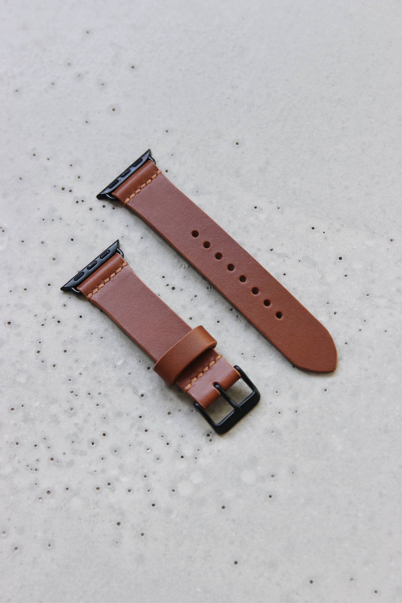 Apple Watch Lederband in Braun auf einem Betonuntergrund.
