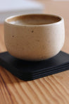 Auf einem Stapel Leder Untersetzer in Schwarz steht eine Kaffeetasse.