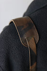 Schulterpad von einem Leder Kameragurt in Camo in Nahaufnahme und über der Schulter getragen.