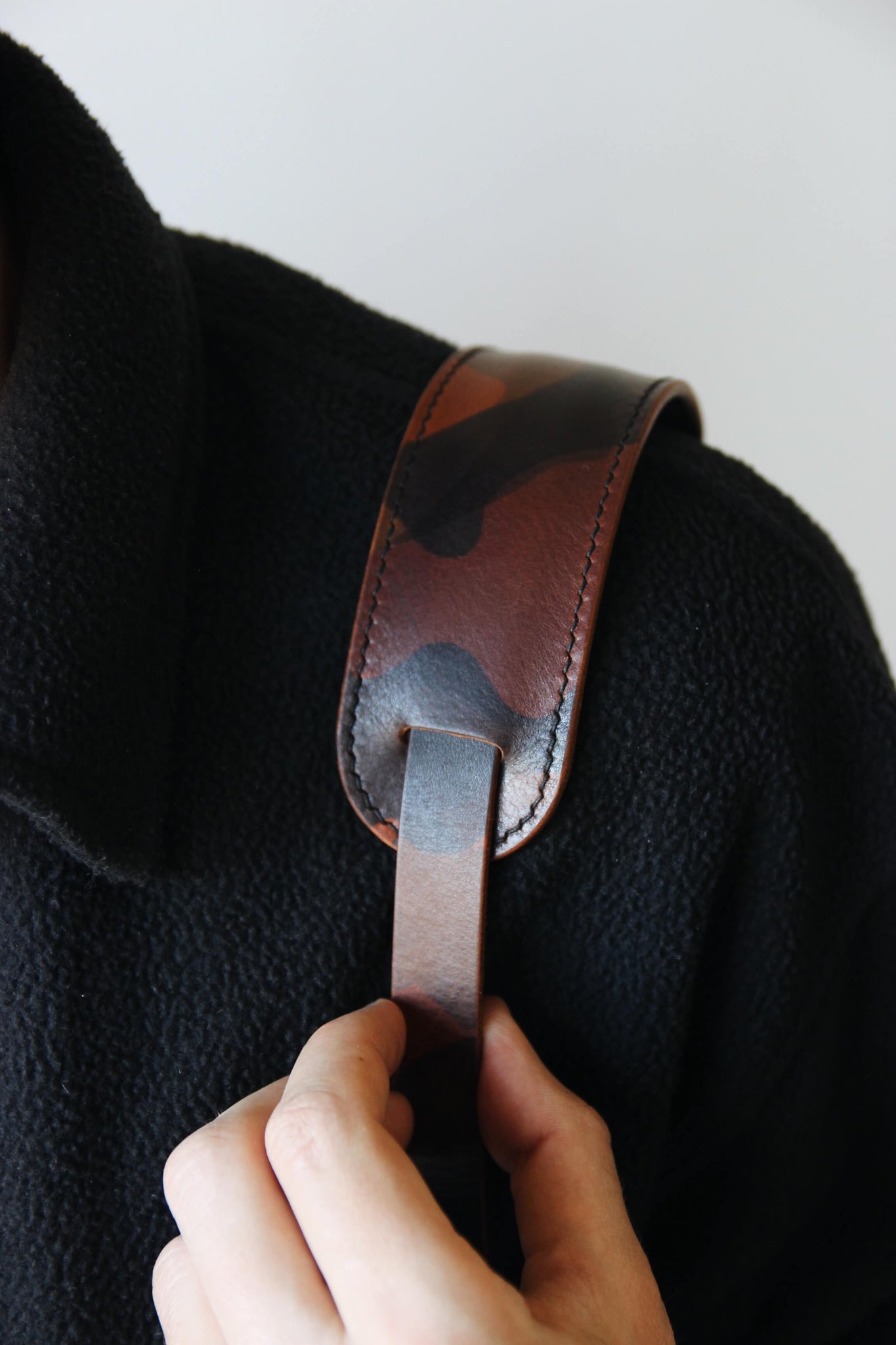 Schulterpad von einem Leder Kameragurt in Camouflage in Nahaufnahme und über der Schulter getragen.