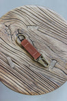 Ein Leder Schlüsselanhänger in Braun mit einem Karabiner und Schlüsselring in Messing Antik auf einem Holzstuhl.