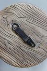 Ein Leder Schlüsselanhänger in Camo mit einem Karabiner und Schlüsselring in Schwarz auf einem Holzstuhl.