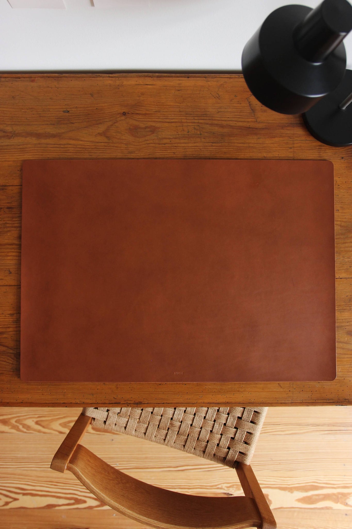 Eine große Leder Schreibtischunterlage in Braun liegt auf einem Schreibtisch aus Holz.