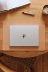 Auf einem Holztisch liegt einer Schreibtischunterlage aus Leder in Natural und auf dieser befindet sich ein zugeklapptes MacBook.