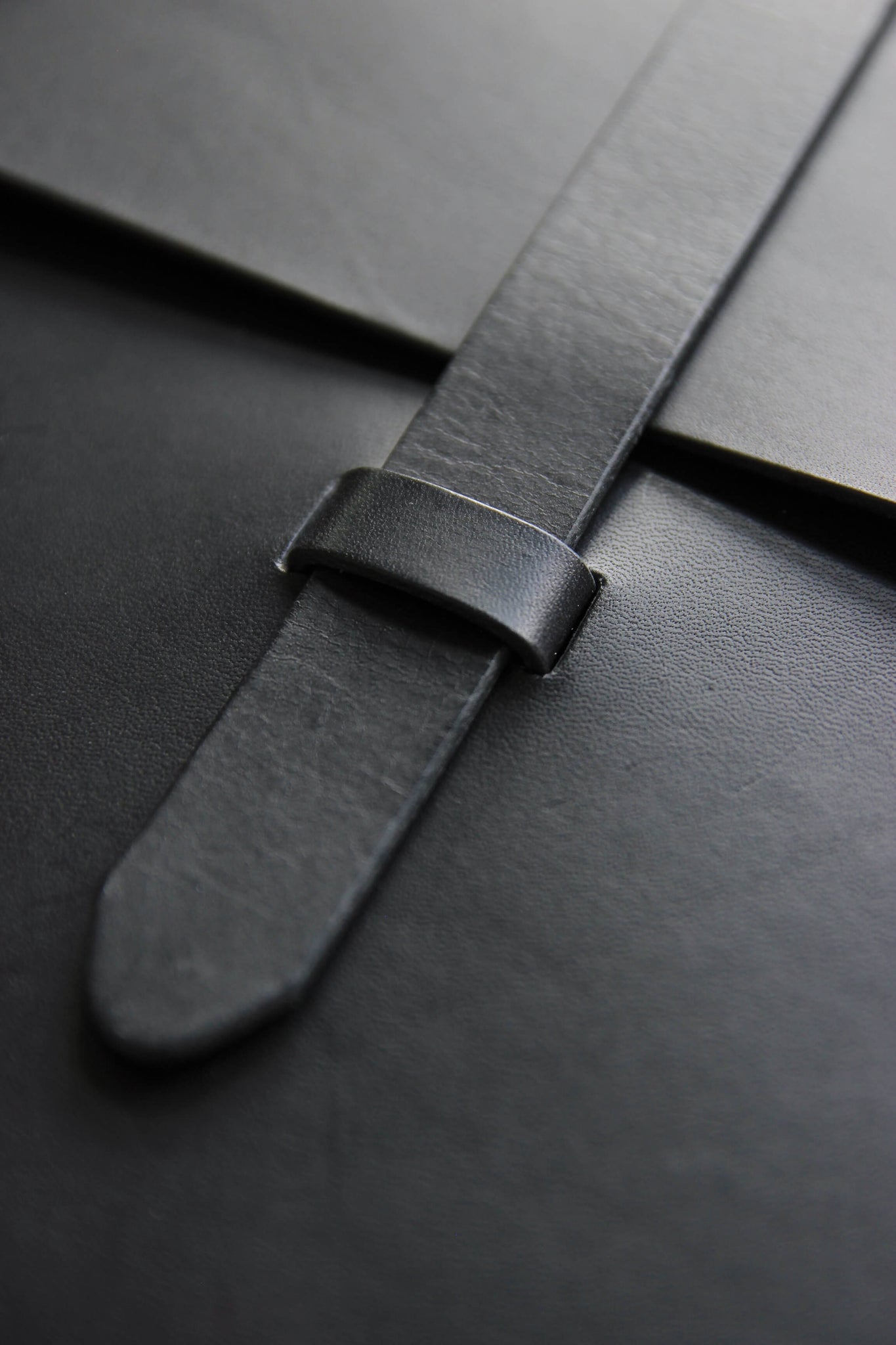 Detailaufnahme des Verschlusses einer MacBook Hülle aus Leder in Schwarz.