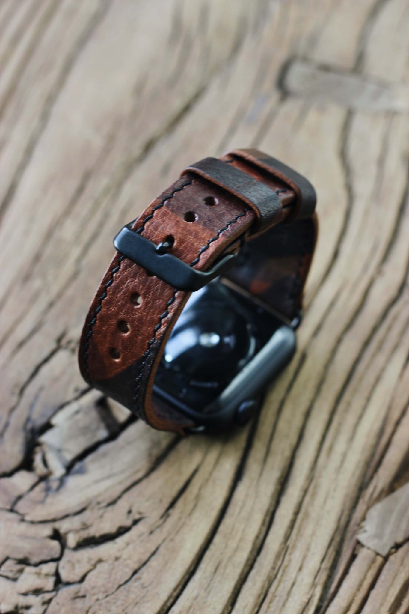 Apple Watch mit einem Apple Watch Lederarmband in Camo auf einer Holzplatte.