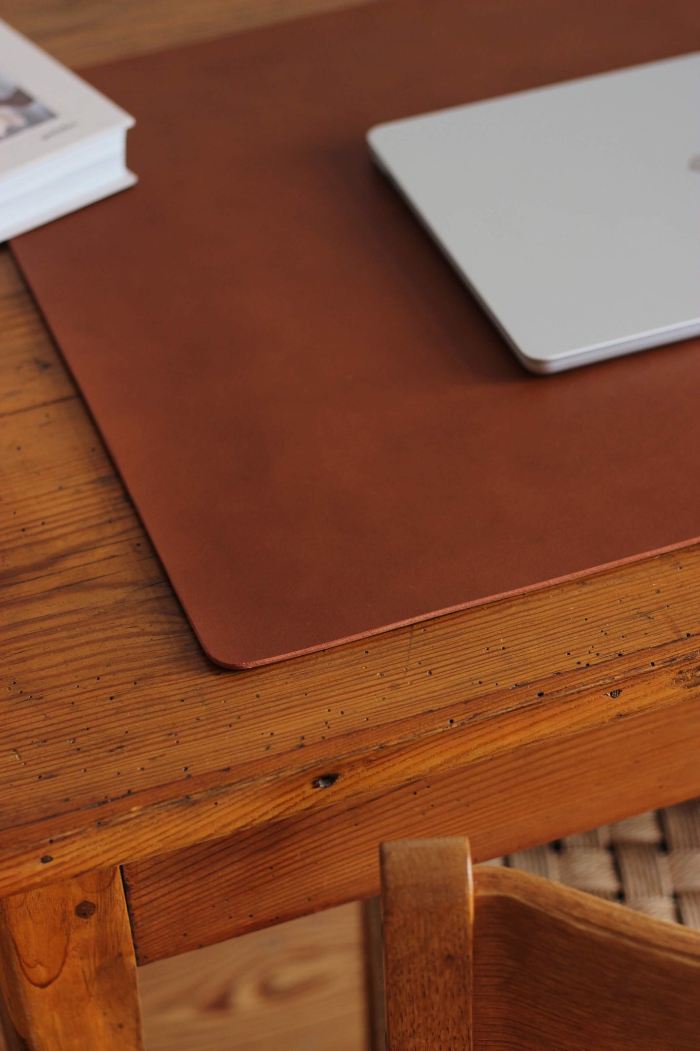 Ausschnitt einer Leder Schreibtischunterlage in Braun auf einem Schreibtisch aus Holz.