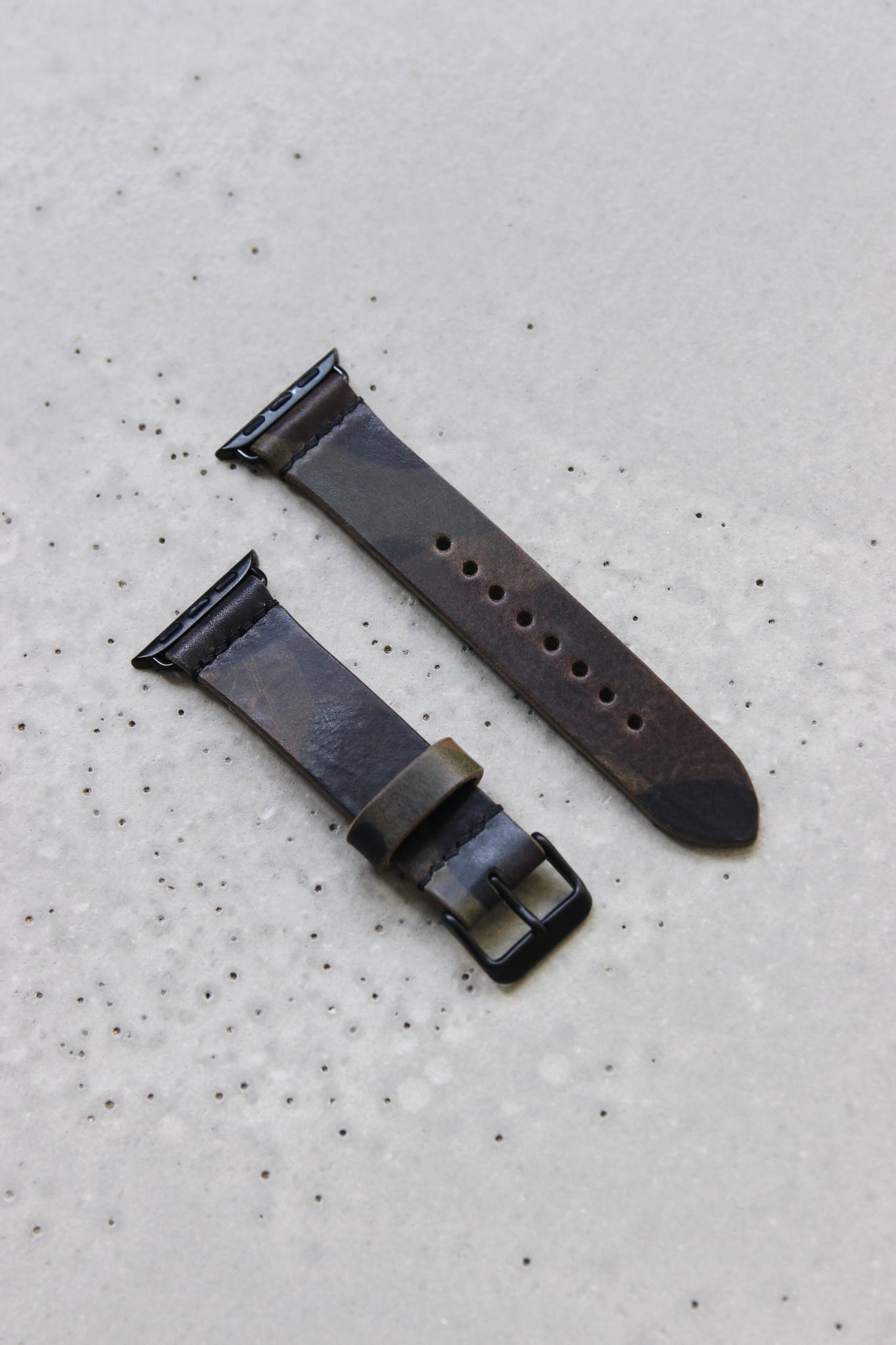 Apple Watch Lederband in Camouflage auf einem Betonuntergrund.