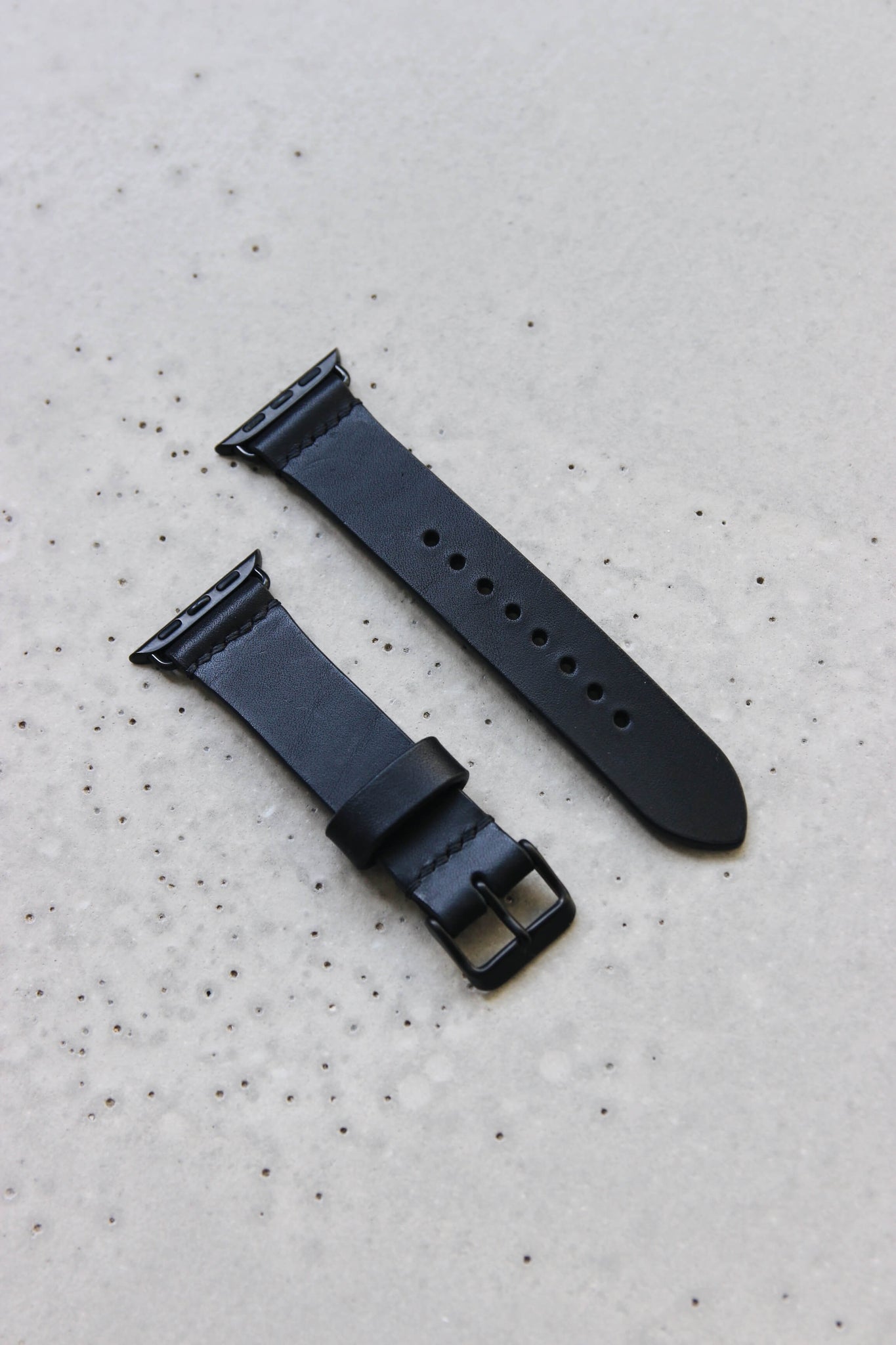 Apple Watch Lederband in Schwarz auf einem Betonuntergrund.