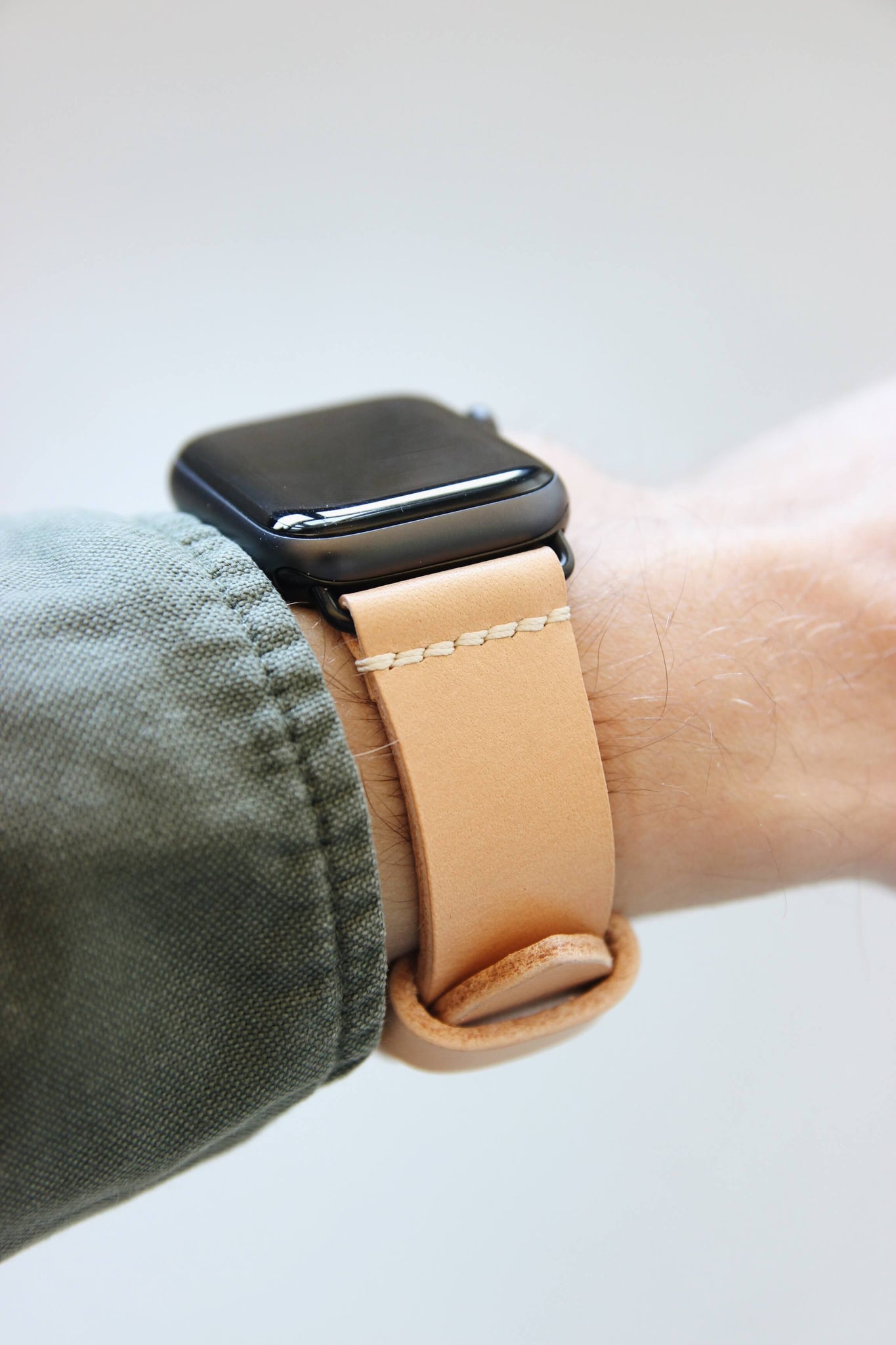 Seitenansicht einer Apple Watch am Handgelenk mit einem Lederband in Natural.