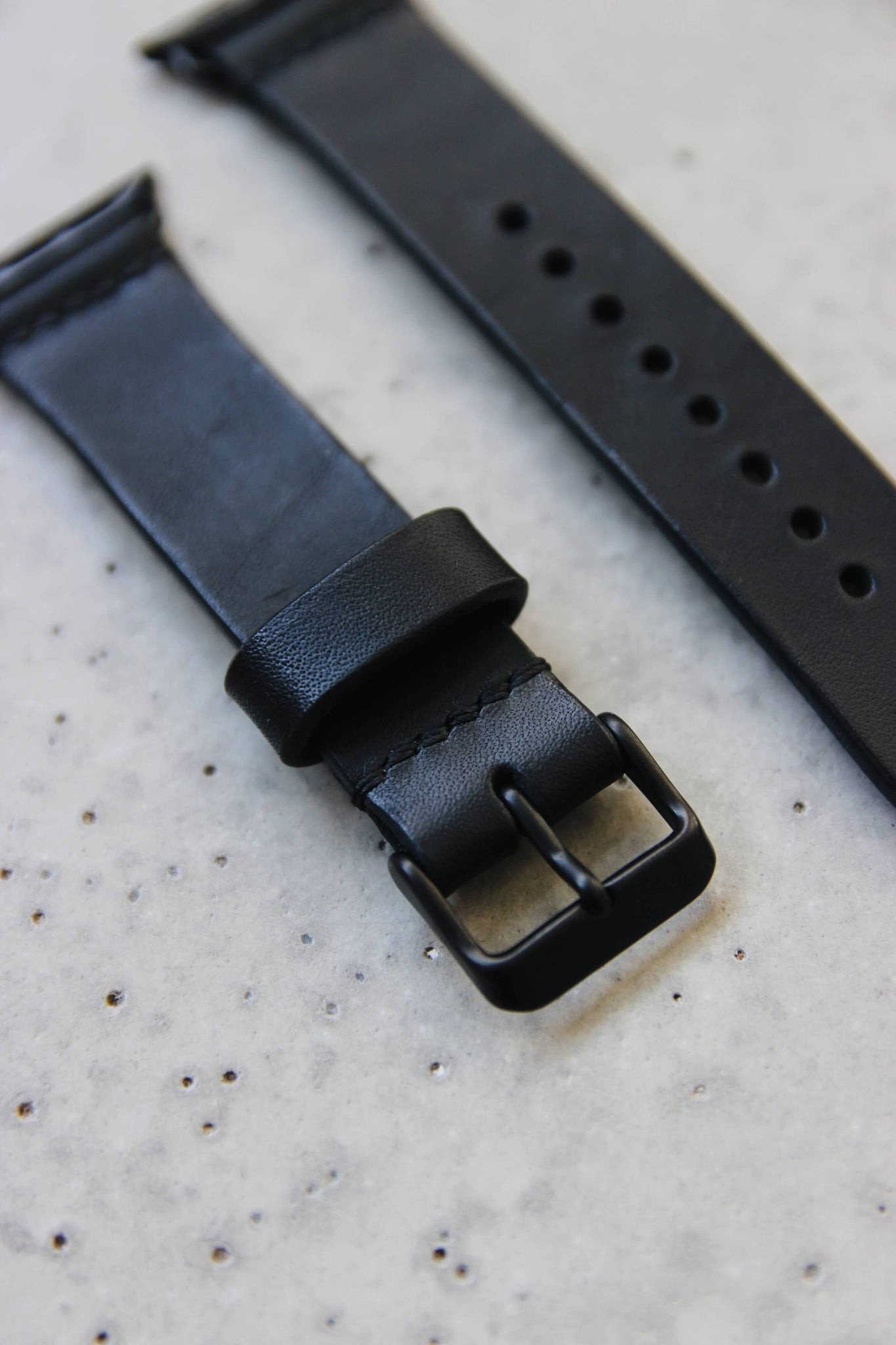 Apple Watch Lederband in Schwarz in Nahaufnahme auf einem Betonuntergrund.