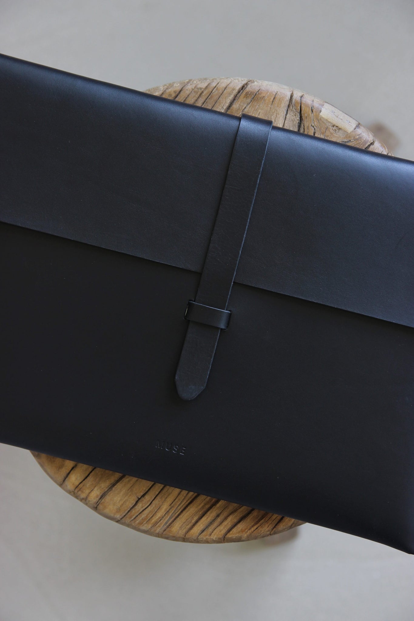 Nahaufnahme einer MacBook Hülle aus Leder in Schwarz auf einem auf Holzstuhl.