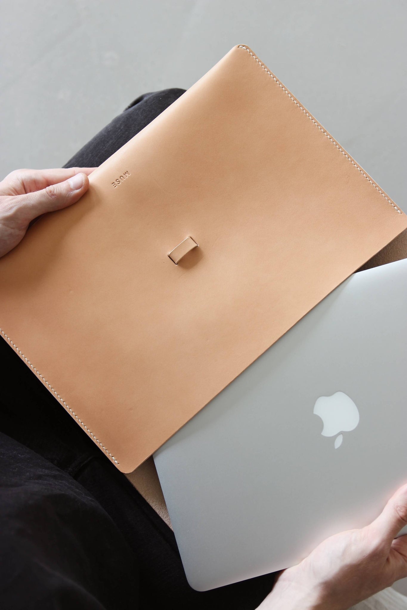 Ein MacBook wird in eine MacBook Hülle aus Leder in Natural geschoben.