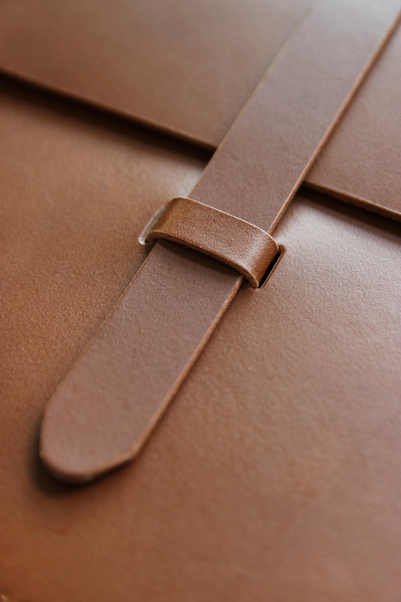 Detailaufnahme des Verschlusses einer MacBook Hülle aus Leder in Braun.