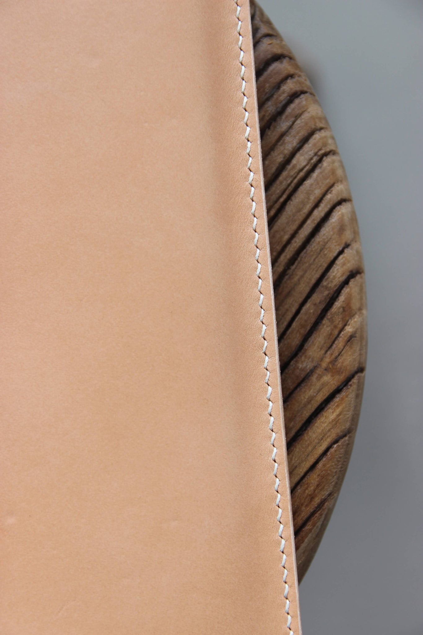 Detailaufnahme der Naht einer MacBook Hülle aus Leder in Natural auf einem Holzstuhl.
