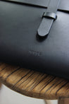 Detailaufnahme des Logos einer MacBook Hülle in Leder in Schwarz.