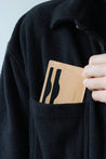 Kartenetui aus Leder in Natural wird in eine Brusttasche eines schwarzen Oberteils gesteckt.