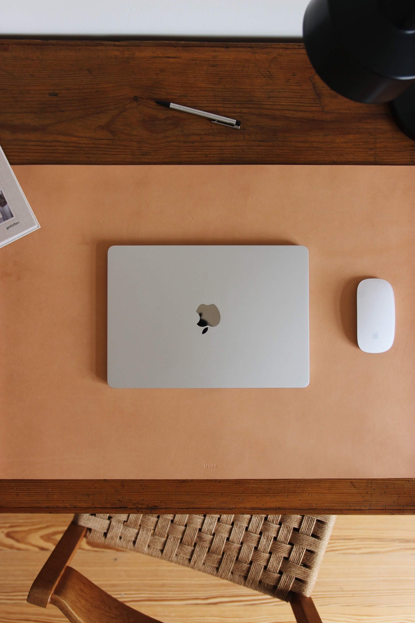 Nahaufnahme einer Leder Schreibtischunterlage in Natural auf einem Schreibtisch aus Holz und auf dieser liegt ein zugeklapptes MacBook und eine Maus.