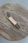 Ein Leder Schlüsselanhänger in Natural mit einem Karabiner und Schlüsselring in Messing Antik auf einem Holzstuhl.