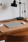 Seitliche Ansicht einer Leder Schreibtischunterlage in Natural auf einem Holzschreibtisch und darauf liegt ein zugeklapptes MacBook und eine Maus.