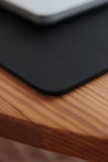 Detailaufnahme der Lederkante von einer Schreibtischunterlage aus Leder in Schwarz.