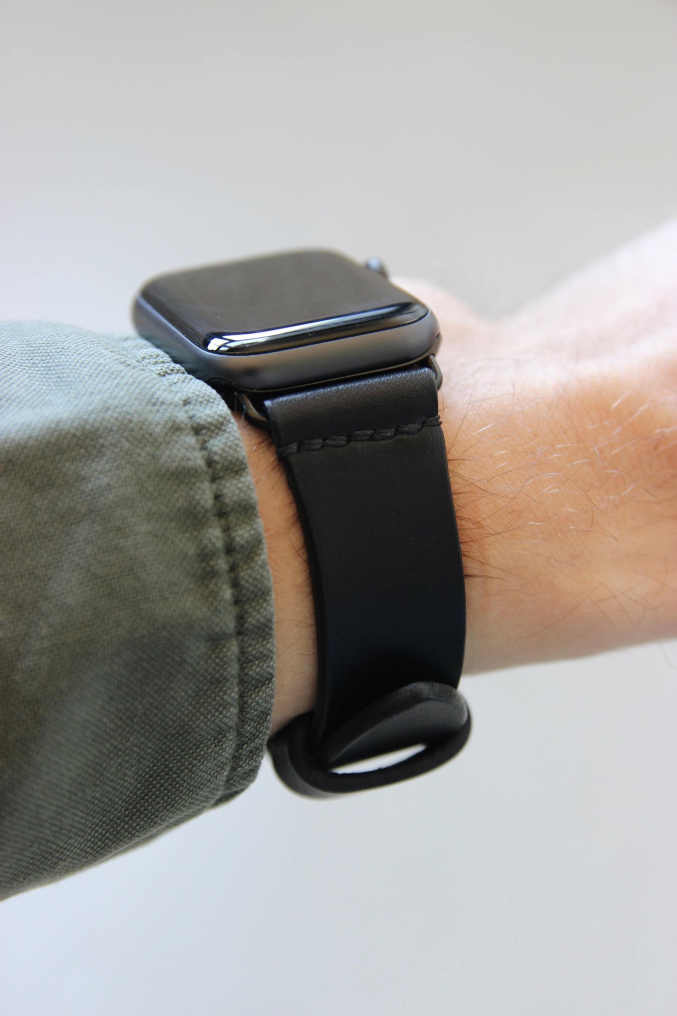 Seitenansicht einer Apple Watch am Handgelenk mit einem Lederband in Schwarz.