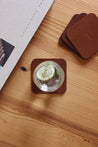 Auf einem Leder Untersetzer in Braun steht ein Wasserglas mit Zitronenscheibe und darüber liegt ein Stapel mit weiteren Leder Untersetzern.